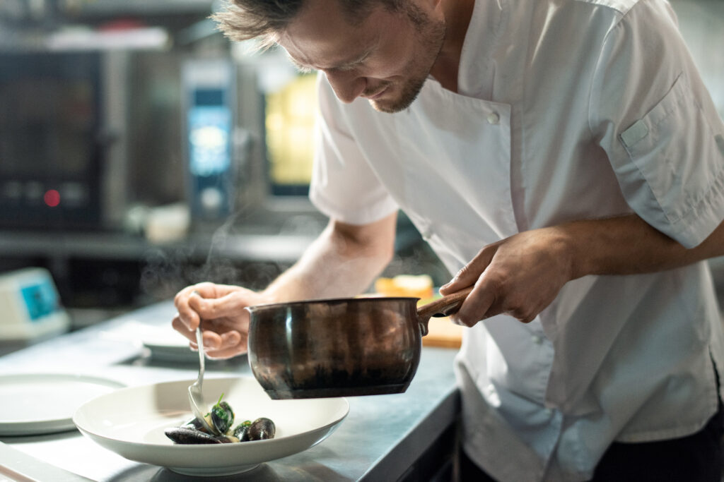 Chef serving up a seafood dish to be enjoyed by a customer.